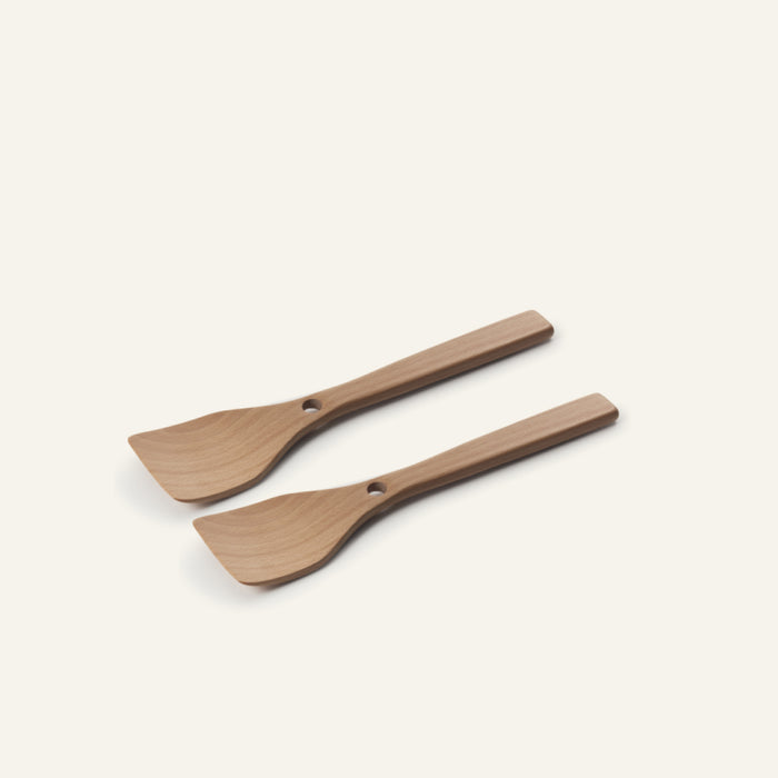Two Beechwood Spatulas with flat, angled heads and rectangular handles—each with a small hole near the top—are displayed on a plain, light background. Ideal as Always Pan accessories or for convenient spatula nesting and storage.