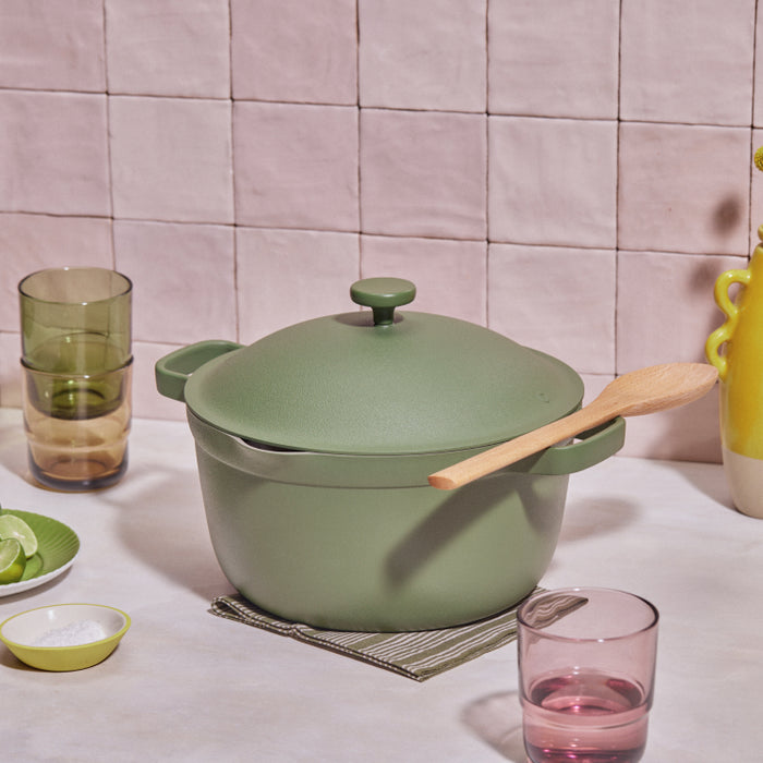 Green perfect pot non toxic nonstick dutch oven resting on a table next to drinking glasses