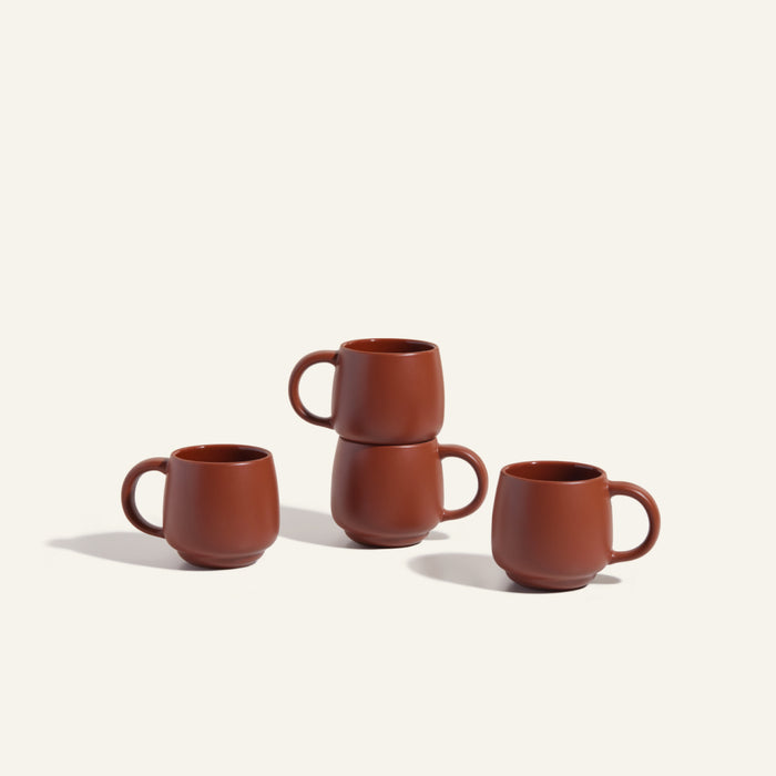 Four Night + Day Mugs in brown ceramic stoneware are displayed on a plain surface, with two mugs stacked and two beside them, highlighting their generous capacity and stylish practicality.