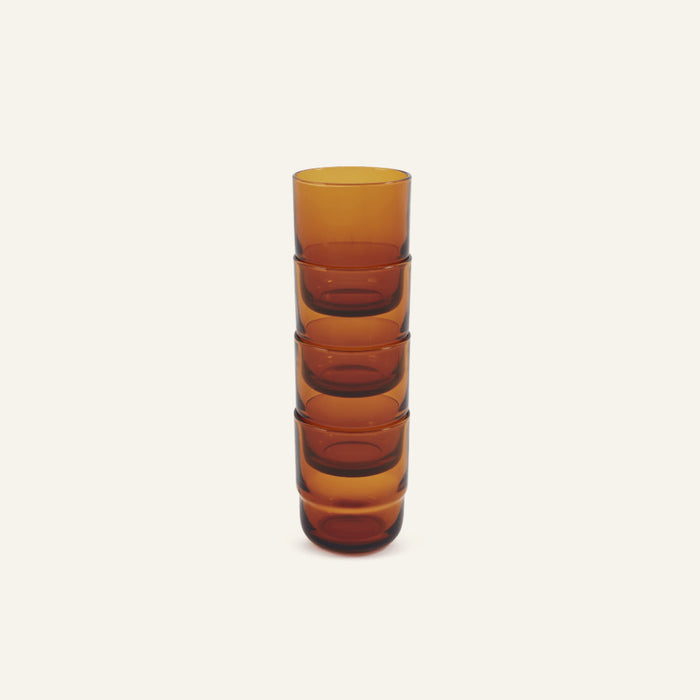 Five Short Night + Day Glasses, in amber color and handmade, are stacked vertically against a plain, light background.