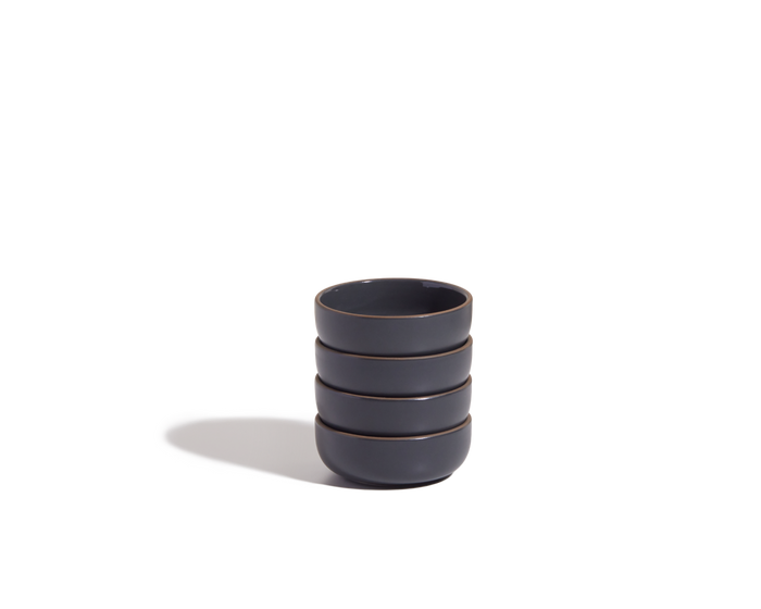 A stack of four Tiny Bowls, made from scratch-resistant ceramic, is arranged on a plain white background and casts a shadow to the left.