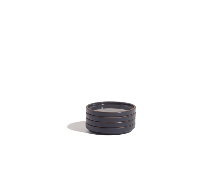 The Tiny Plates are small, round, dark gray ceramic plates with horizontal ridges along the sides, ideal as snack plates and showcased on a plain white background.